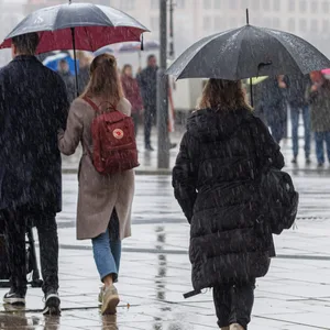 Passanten mit Schirmen an der Alster