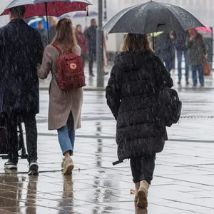 Hamburger gehen bei Regen mit Schirmen auf dem Jungfernstieg.