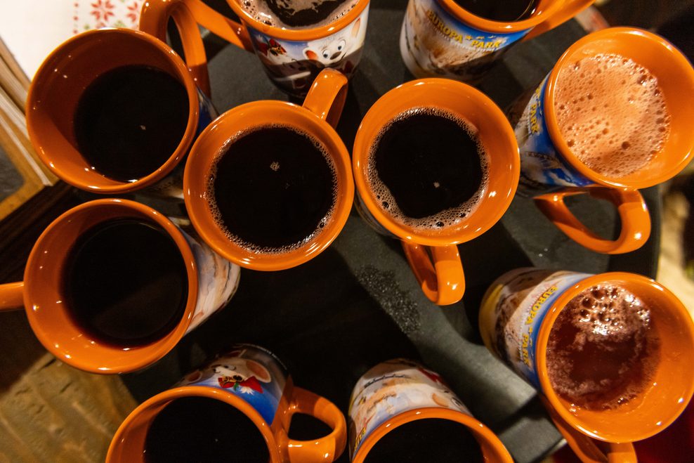 Becher mit Glühwein und Früchtepunsch stehen auf einem Tablett.