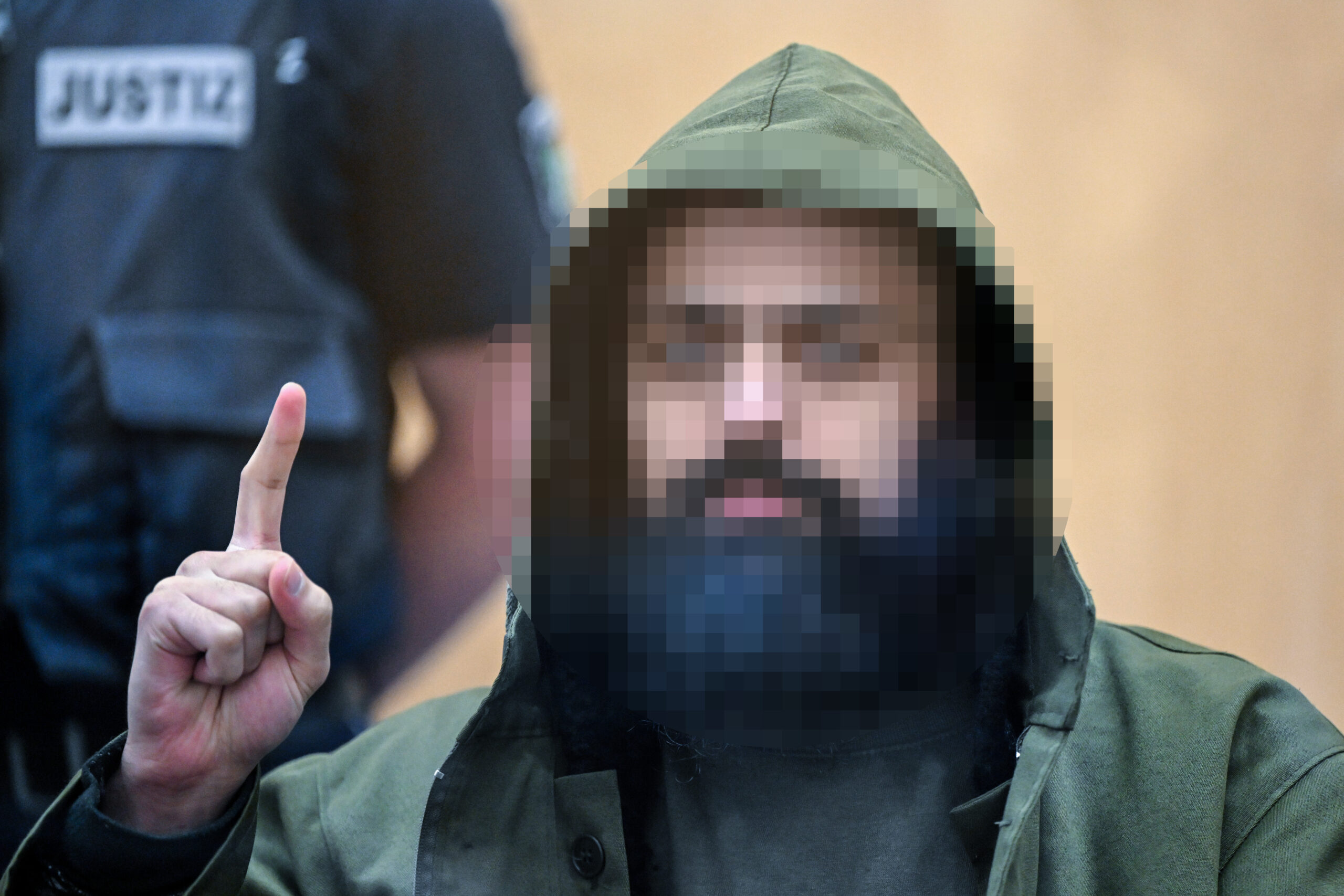 Der Angeklagte Maan D. wartet im Prozess um die Messerattacken von Duisburg auf den Beginn der Verhandlung und zeigt den Gruß der Kämpfer des IS, Tauhid.