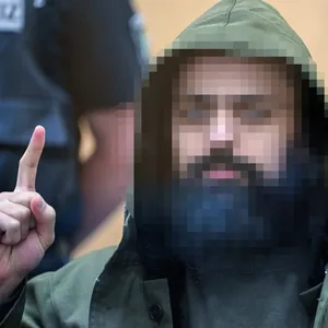 Der Angeklagte Maan D. wartet im Prozess um die Messerattacken von Duisburg auf den Beginn der Verhandlung und zeigt den Gruß der Kämpfer des IS, Tauhid.