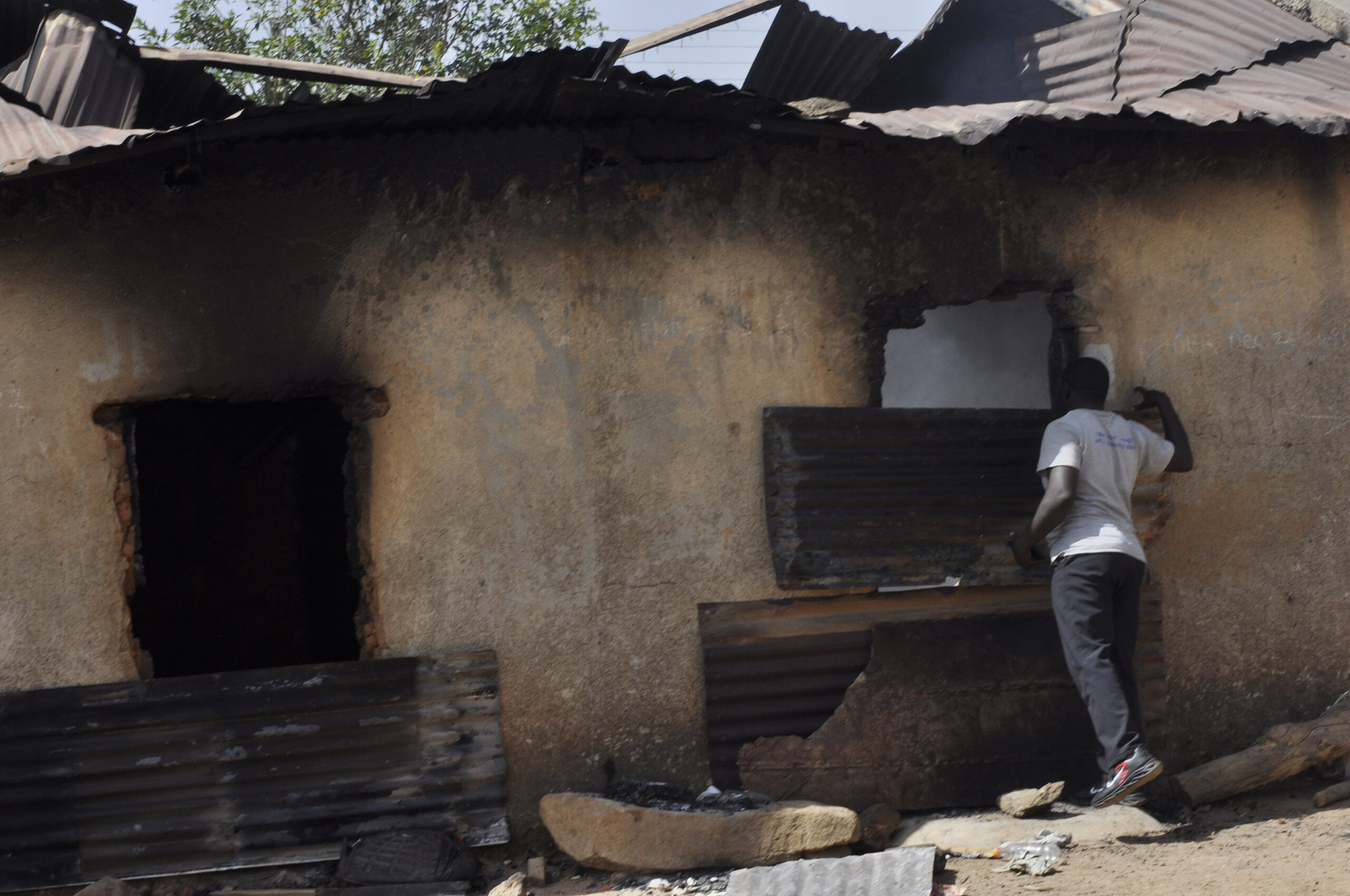 Ein Mann inspiziert nach einem Angriff ein ausgebranntes Haus.