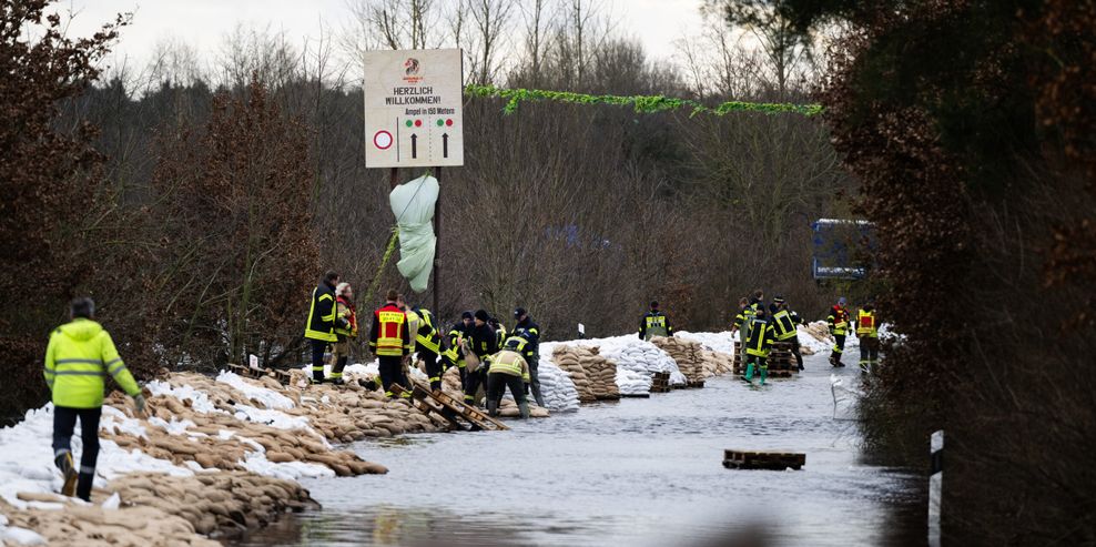 Einsatzkräfte von Feuerwehr und THW schütteten provisorische Dämme auf, um die Stallungen der Tiere abzusichern.