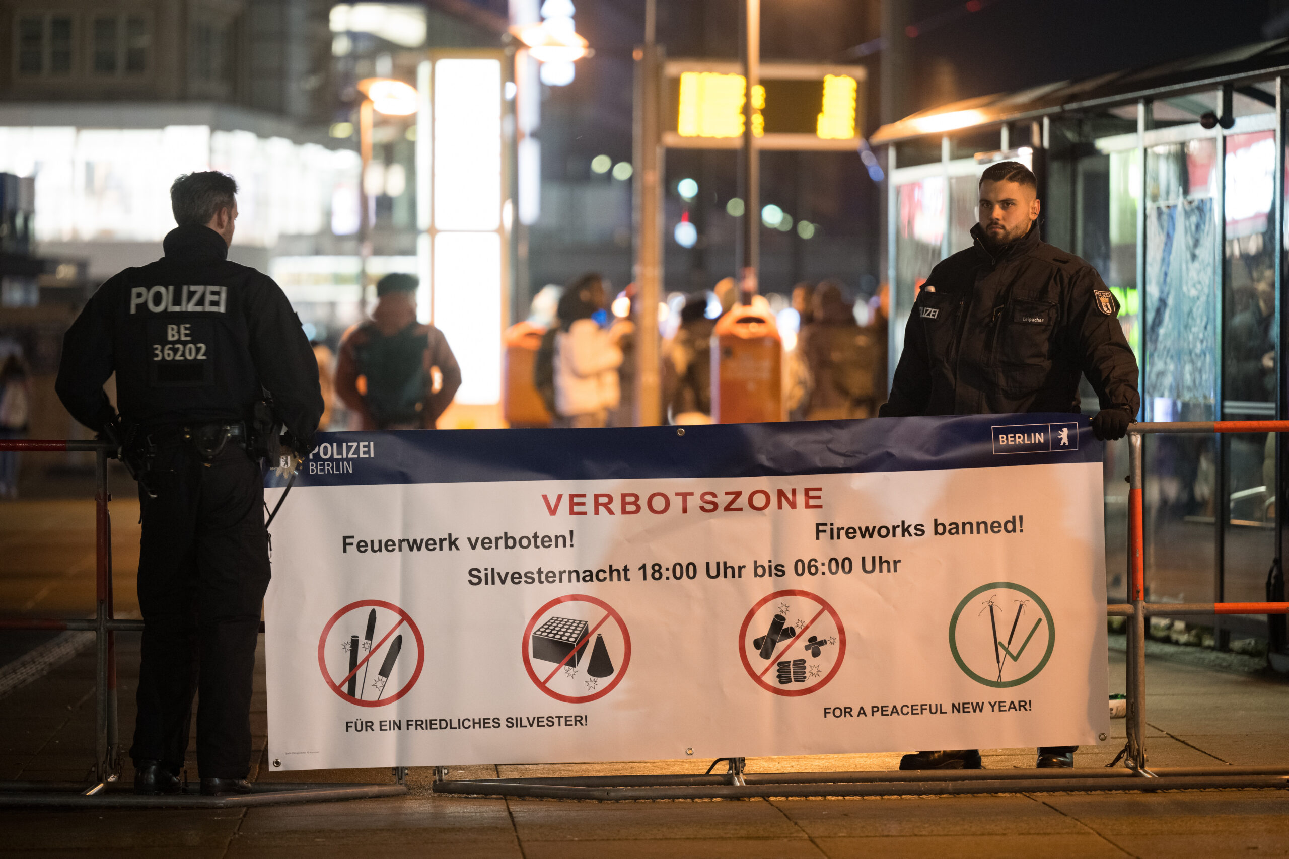 Polizeibeamte stehen an der Böllerverbotszone am Alexanderplatz an einem Hinweisschild.