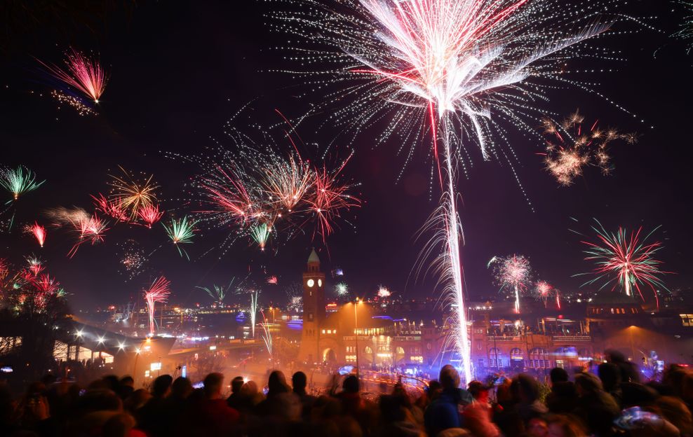 Zahlreiche Menschen feiern den Jahreswechsel auf Sankt Pauli über den Landungsbrücken am Hafen.