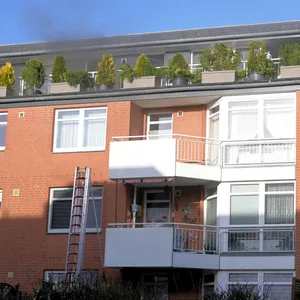 Mehrfamilienhaus, aus dem Dachgeschoss dringt Rauch