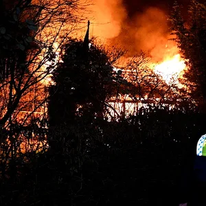 Polizisten stehen vor der brennenden Laube.