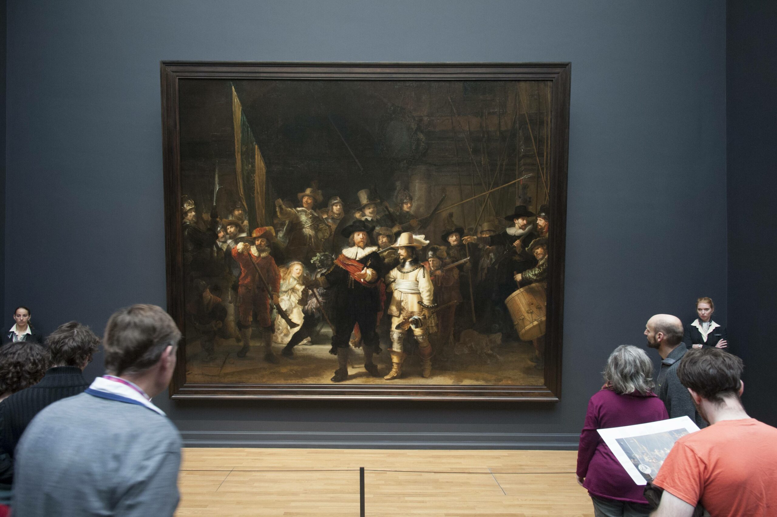 Besucher stehen vor dem von zwei Museumswächtern bewachten Gemälde Nachtwache von Rembrandt van Rijn im Rijksmuseum in Amsterdam.