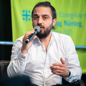 Der Politiker Tareq Alaows, der am Freitag bei den Grünen ausgetreten ist, sitzt bei einer Podiumsdiskussion auf dem Evangelischen Kirchentag in Nürnberg 2023. (Archivbild)