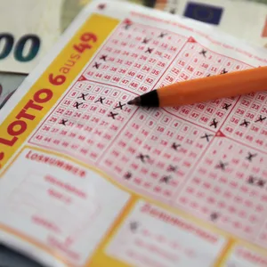 Ein ausgefüllter Lottoschein, ein Stift und Geldscheine liegen auf einem Tisch. (Symbolbild)