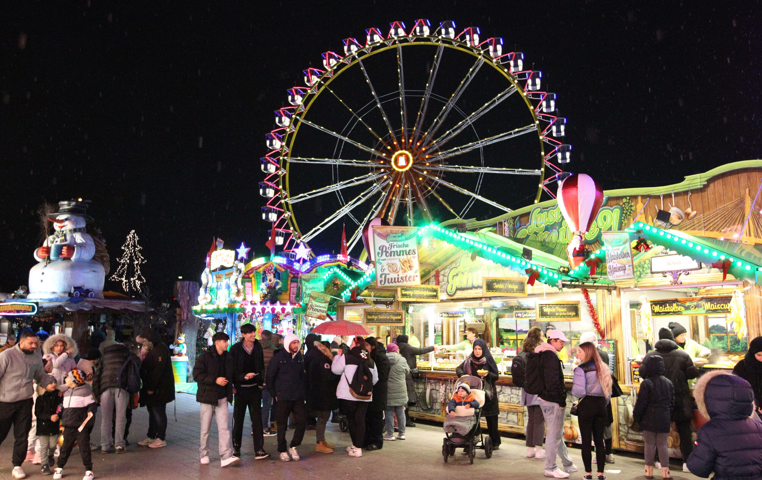 Der Winterdom: Besucher vor Buden, im Hintergrund das Riesenrad