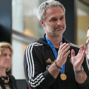 Christian Wück, mit der Goldmedaille um den Hals, applaudiert.