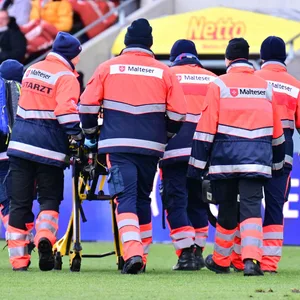 Simon Handle wird von Sanitätern von Platz gefahren