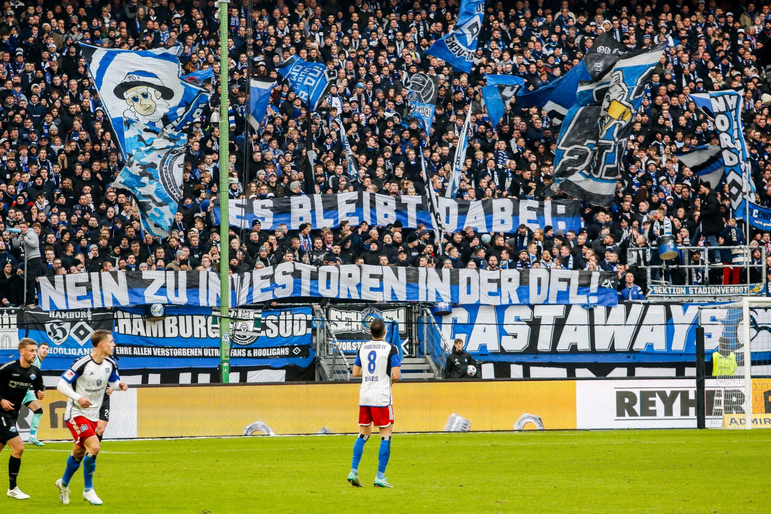 HSV-Fans zeigen ein Banner, auf dem gegen den Investoren-Deal der DFL protestiert wird.
