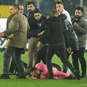 Schiedsrichter Halil Umut Meler liegt am Boden, um ihn herum stehen Spieler und Betreuer.