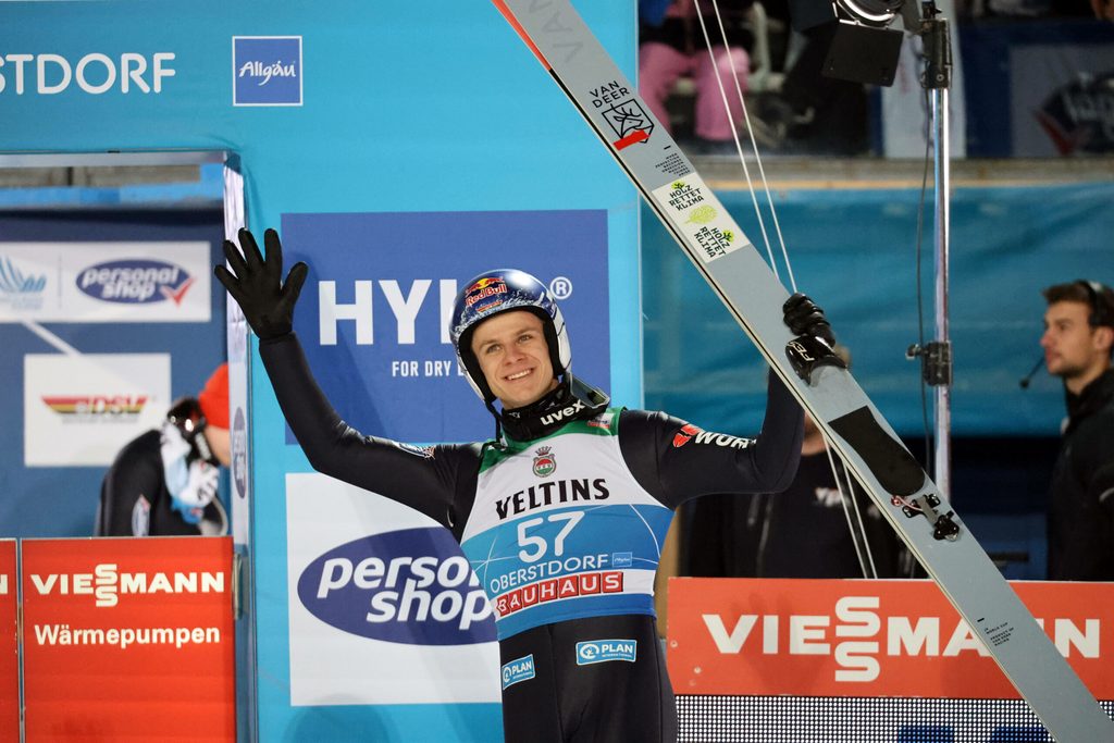 Andreas Wellinger jubelt. Unter dem linken Arm ist ein Loch im Anzug zu sehen.