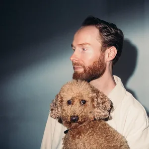 Bunger schaut auf die Seite, im Arm hält er einen Hund