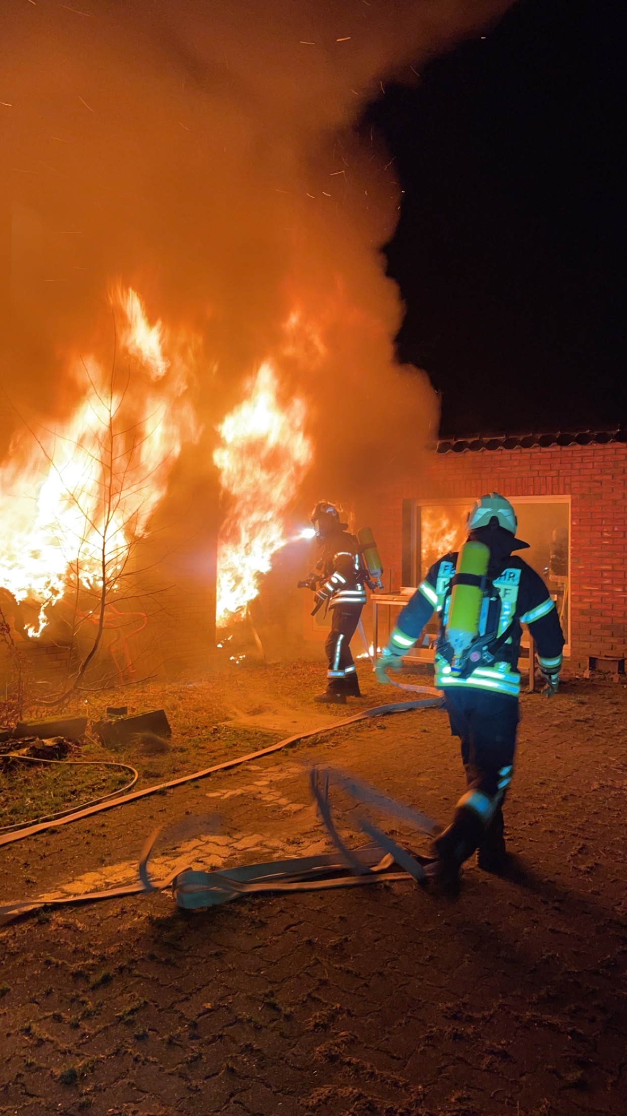 Brand in Kisdorf: Feuerwehrmänner vor einem Haus, aus dem Flammen lodern