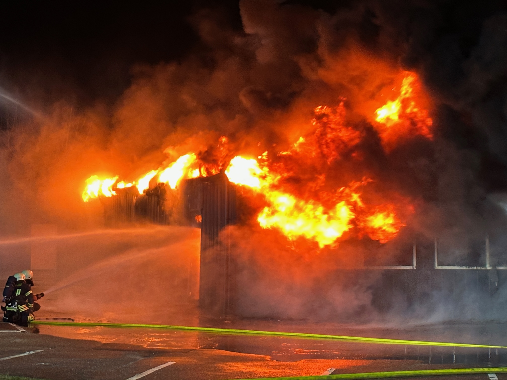 Feuerwehrleute löschen einen in Flammen stehenden Gebäudekomplex in Heiligenhafen.