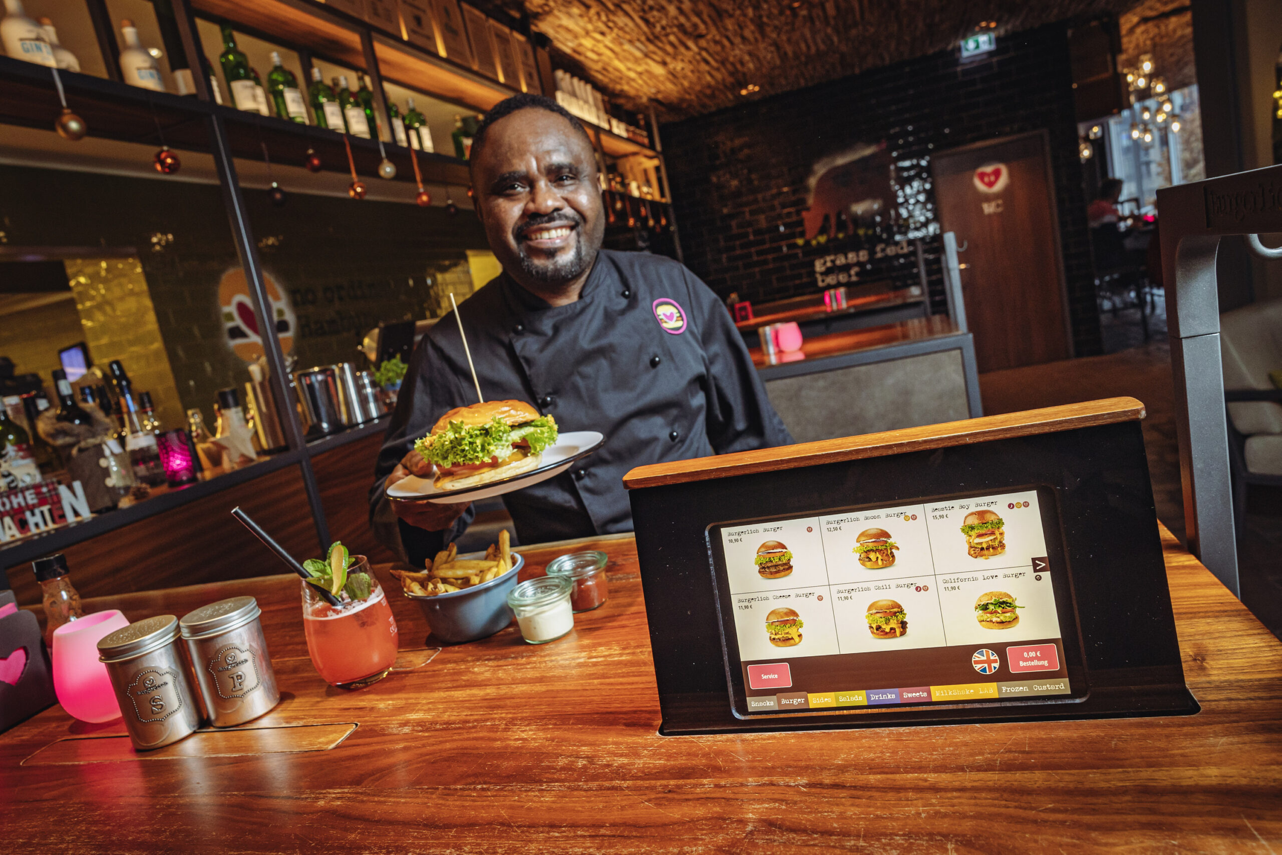 Bei „Burgerlich“, hier am Gänsemarkt, wird das Essen per iPad bestellt. Mitarbeiter Yawo Tenge (56) serviert den Burger.