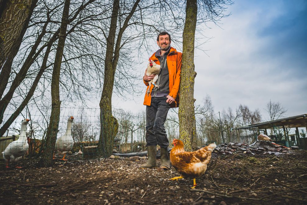 Peter Schultes steht mit einem Huhn auf dem Arm im Entdeckergarten