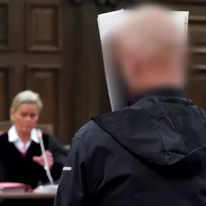 Der Angeklagte steht im Sitzungssaal im Strafjustizgebäude, im Hintergrund sitzt Jessica Koerner, Vorsitzende Richterin am Landgericht.