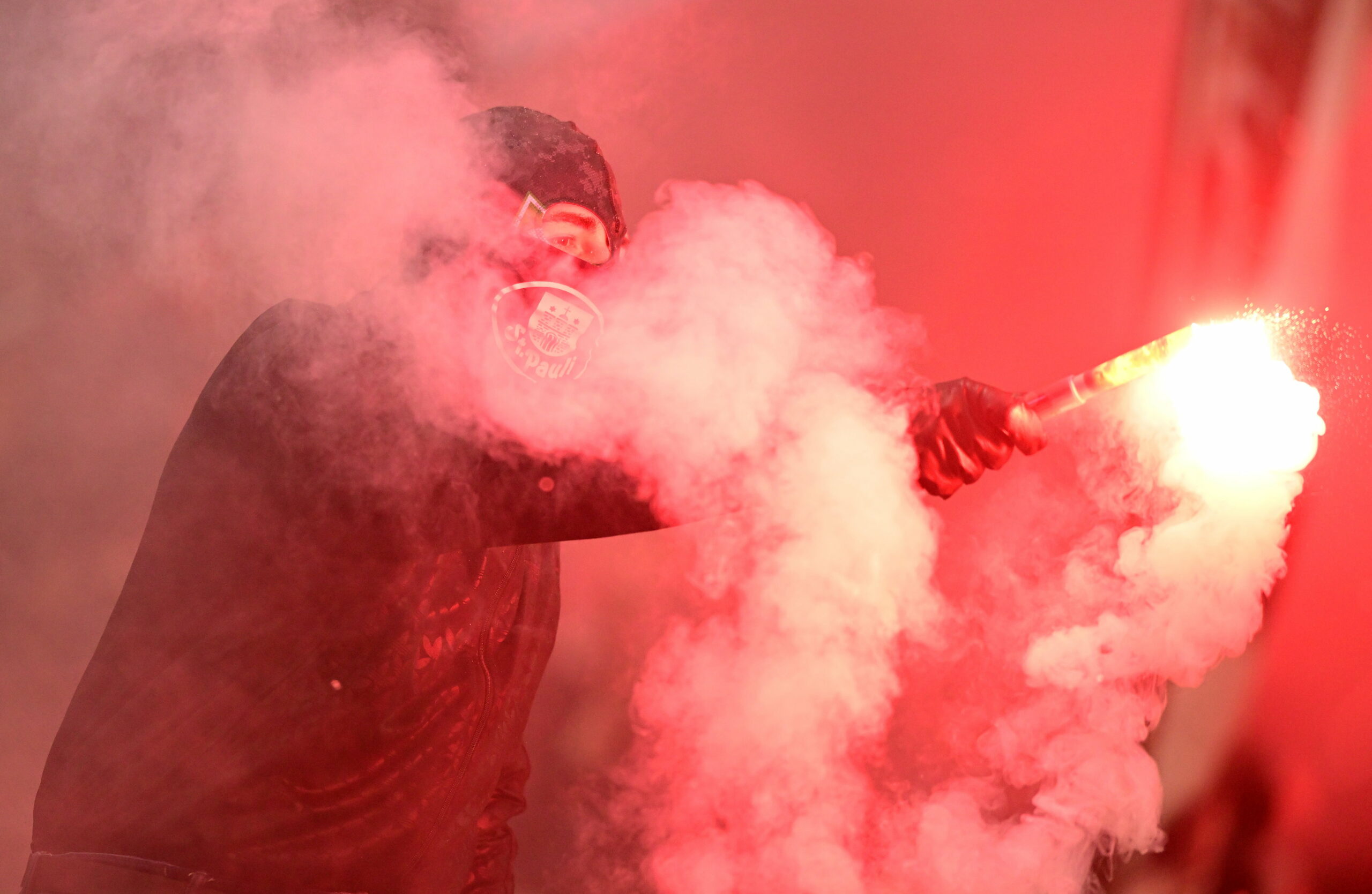 Ein St. Pauli Fan mit Sturmhaube und Pyrotechnik in der Hand