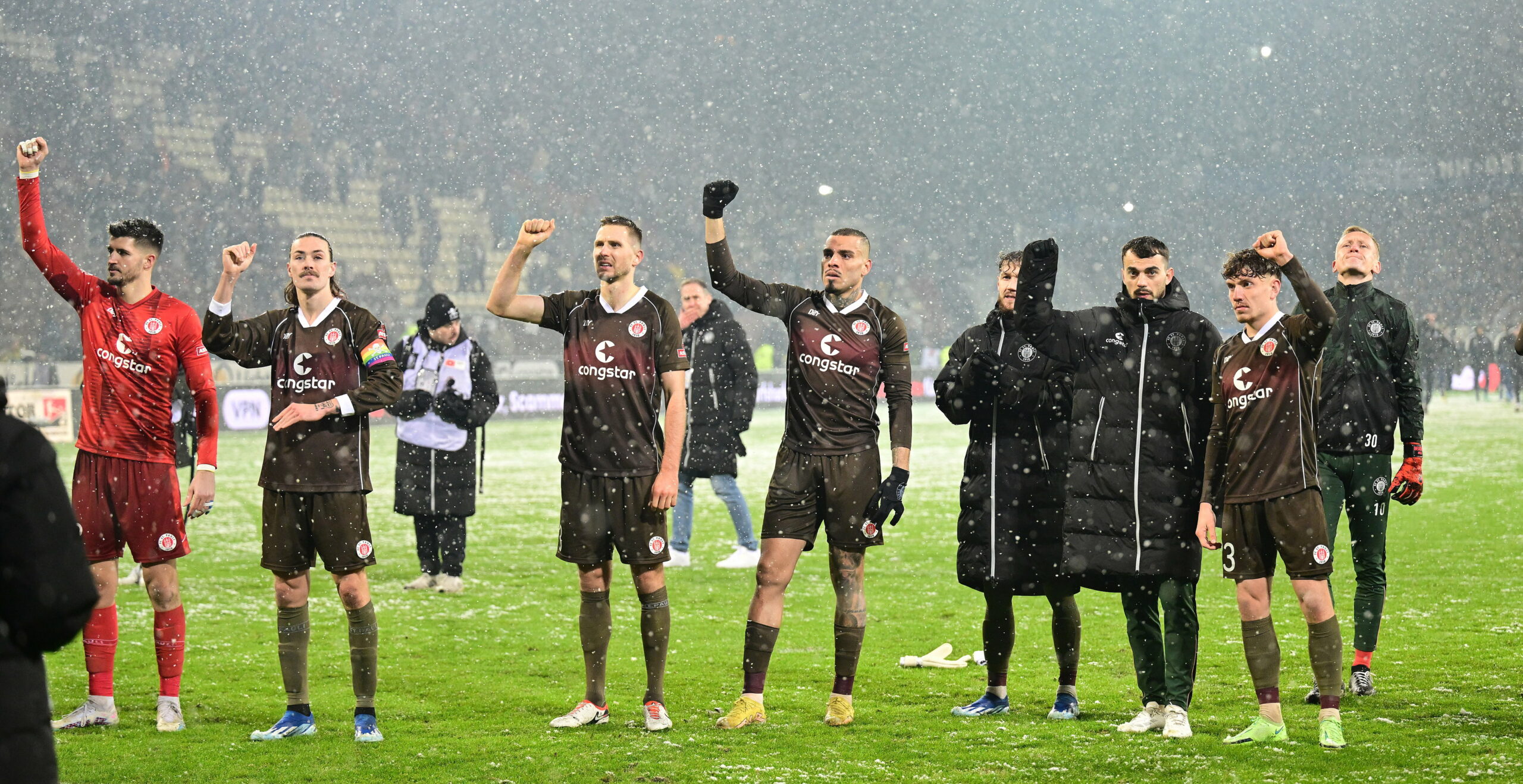 St. Pauli-Profis stehen vor ihren Fans und ballen die Siegerfaust.