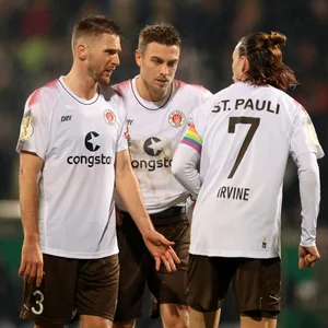 Karol Mets, Hauke Wahl und Jackson Irvine sprechen auf dem Platz beim Pokalspiel in Homburg.