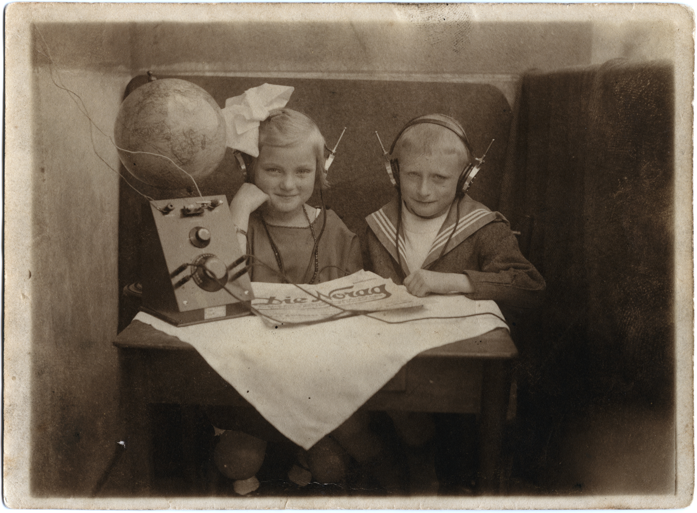 Werbepostkarte der NORAG aus dem Jahr 1924: Zwei Kinder sitzen vor ihrem Empfangsgerät und hören begeistert zu. Vor allem der Funkheinzelmann, Galionsfigur der NORAG, hat es Kindern damals angetan.