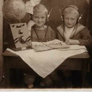 Werbepostkarte der NORAG aus dem Jahr 1924: Zwei Kinder sitzen vor ihrem Empfangsgerät und hören begeistert zu. Vor allem der Funkheinzelmann, Galionsfigur der NORAG, hat es Kindern damals angetan.