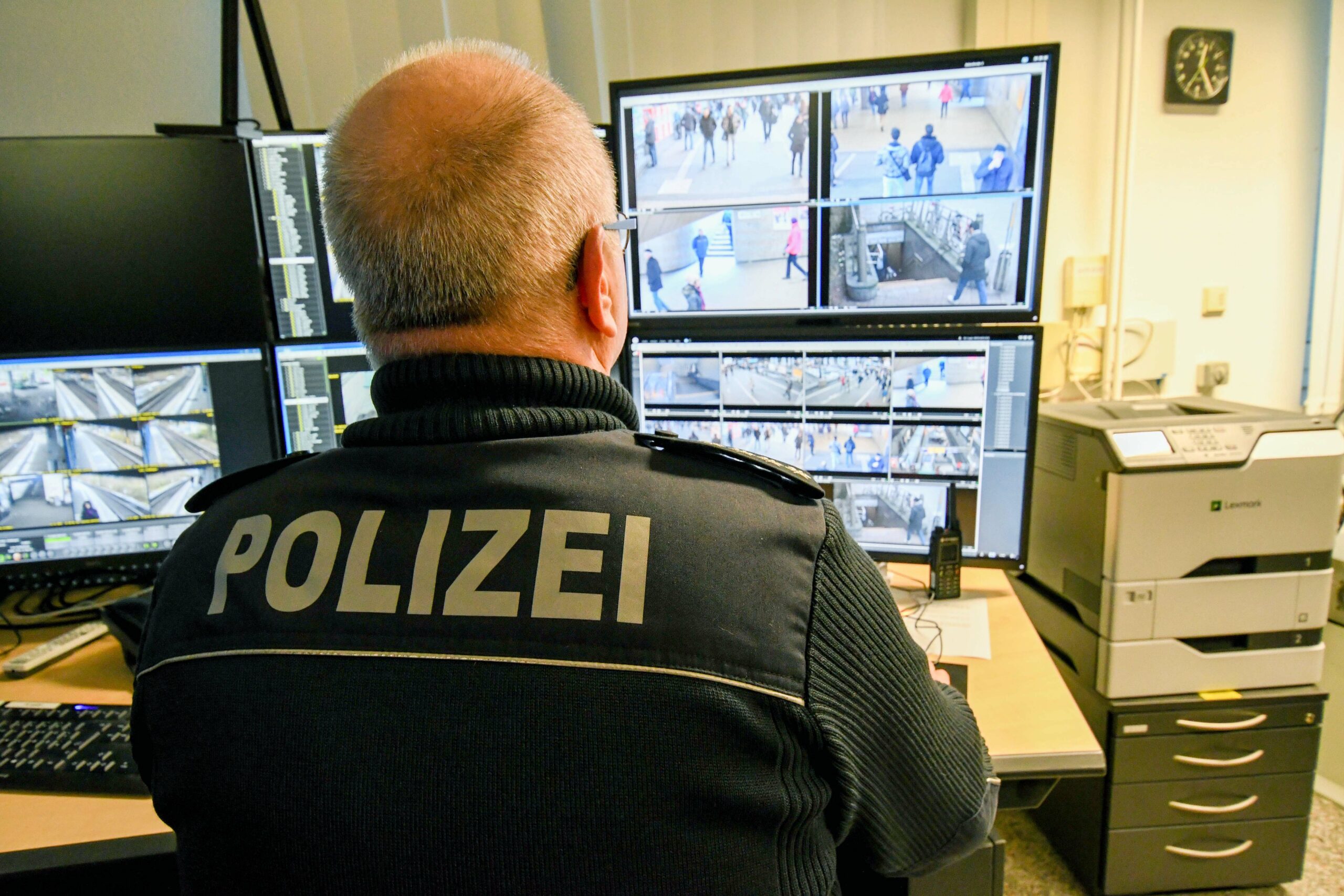 Ein Polizist sitzt vor Monitoren, auf denen Bilder einer Videoüberwachung zu sehen sind.