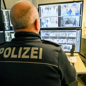 Ein Polizist sitzt vor Monitoren, auf denen Bilder einer Videoüberwachung zu sehen sind.