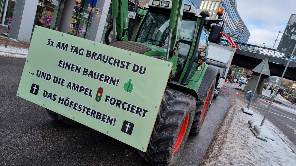 Ein Schild mit der Botschaft „3x am Tag brauchst du einen Bauern ... und die Ampel forciert das Höfesterben“ hängt an der Front eines Treckers.