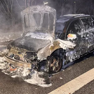 Der Skoda steht am Straßenrand, Front und Motorrad sind verbrannt, das Auto ist mit Löschschaum bedeckt.