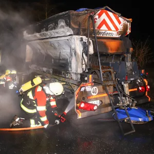 Feuerwehrkräfte löschen das in Brand geratene Streufahrzeug.