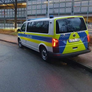 Ein Fahrzeug der Polizei Stade steht am Tatort nahe des Bahnhofs. Rechts ist das Parkhaus zu erkennen, links stehen im Hintergrund kahle Bäume.