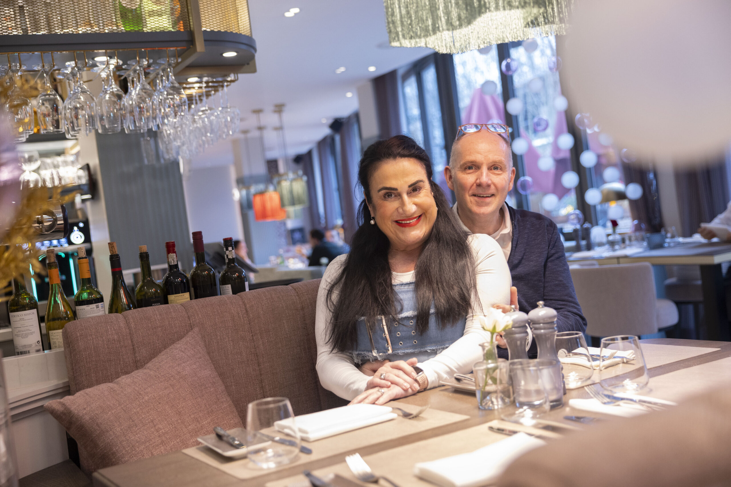 Bianca und Wolfgang Vollheide sitzen in ihrem Restaurant und lächeln in die Kamera