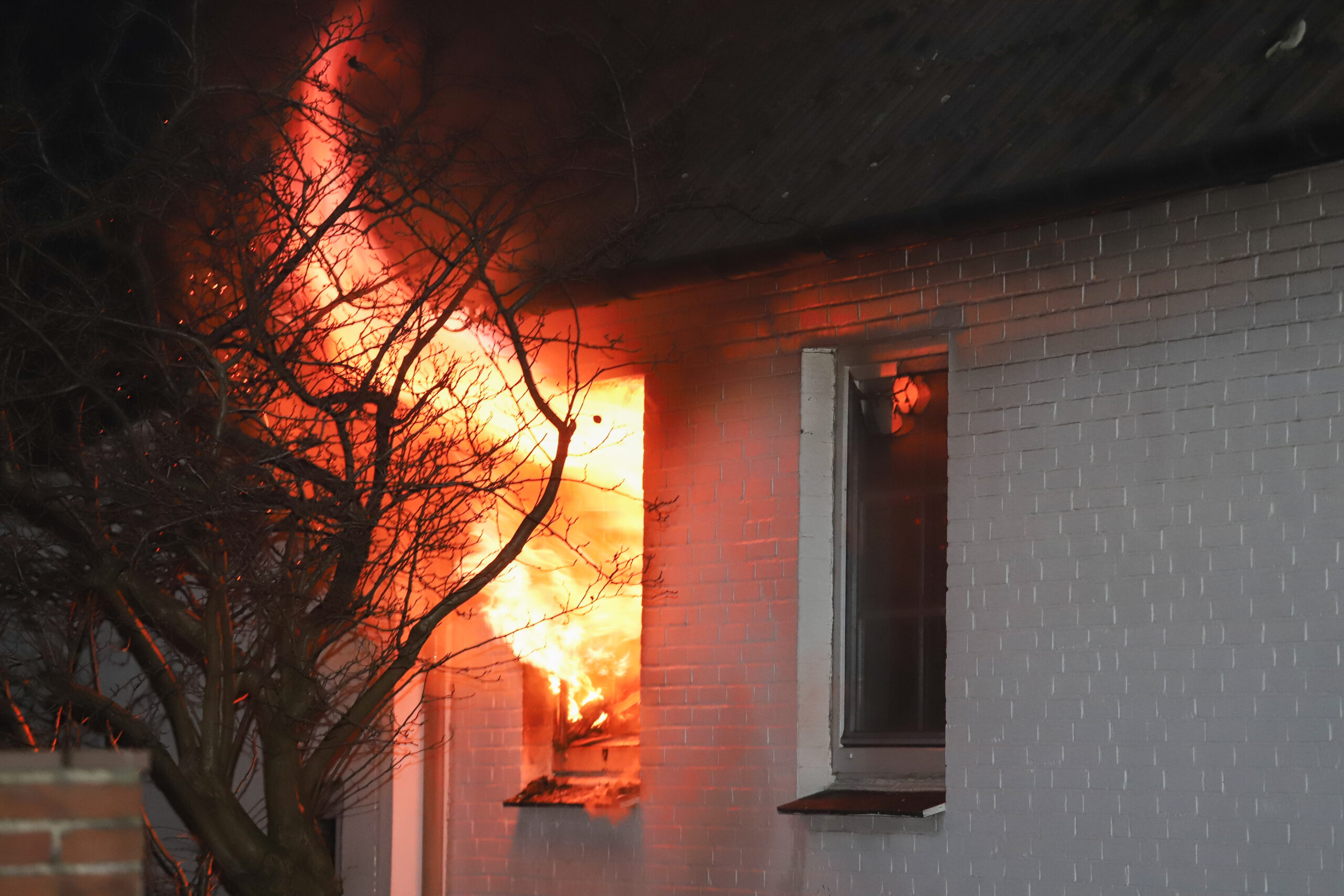 Flammen schlagen aus einem Fenster im Erdgeschoss des Hauses in Itzehoe.