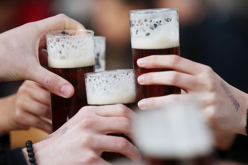 Gäste stoßen an einem Tisch im Außenbereich eines Lokals mit Altbier an