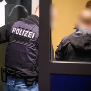 Polizei geht durch eine Glastür in ein Haus