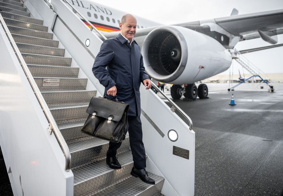 Scholz kommt mit Tasche aus Flugzeug