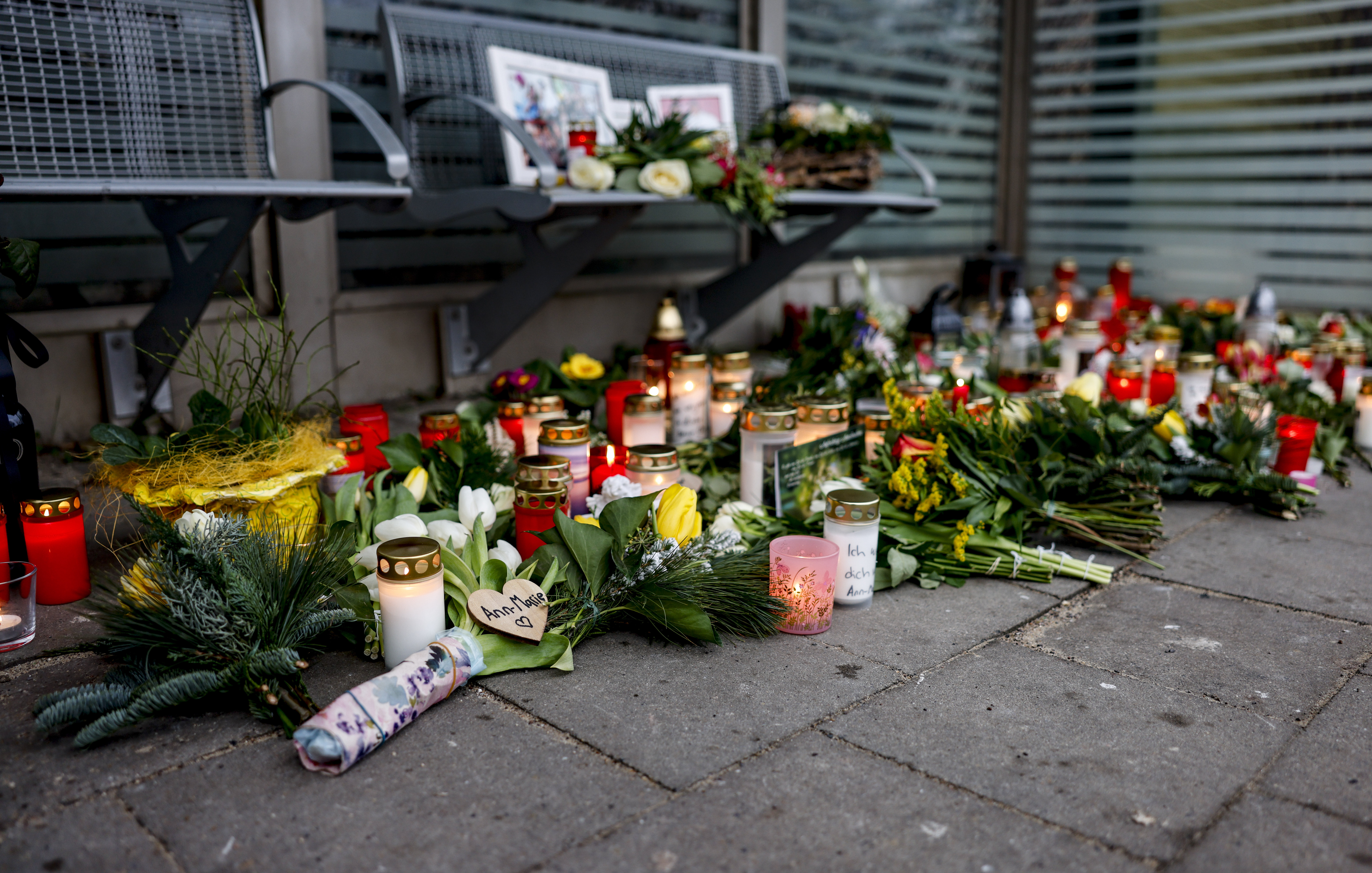 Blumen, Kerzen und verschiedene Bilder liegen im Wartehäuschen am Bahnhof zum Gedenken an die Opfer der Messerattacke.
