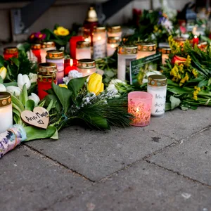 Blumen, Kerzen und verschiedene Bilder liegen im Wartehäuschen am Bahnhof zum Gedenken an die Opfer der Messerattacke.