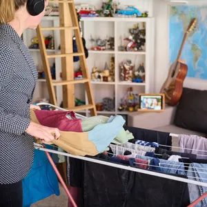 Eine Frau vor einem Wäscheständer, der in einem vollgepackten Kinderzimmer steht (Symbolbild)