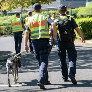 Mit einem Spürhund durchsuchen Polizeibeamte das Gebiet am Schulzentrum in Lohr am Main. (Archivbild)
