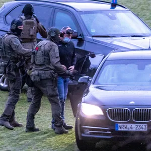 Mit schalldichten Kopfhörern und einer blickdichten Brille wird Thomas Drach von Spezialkräften der Polizei zur Urteilsverkündung gebracht.