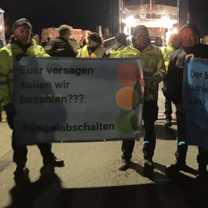 Landwirte stehen mit Plakaten mit der Aufschrift „Euer Versagen sollen wir bezahlen??? #ampelabschalten“ am Fähranleger in Schlüttsiel.