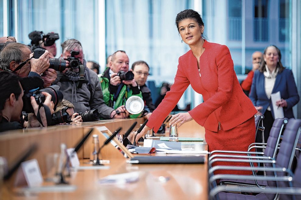 Sahra Wagenknecht im roten Kostüm vor Pressefotografen