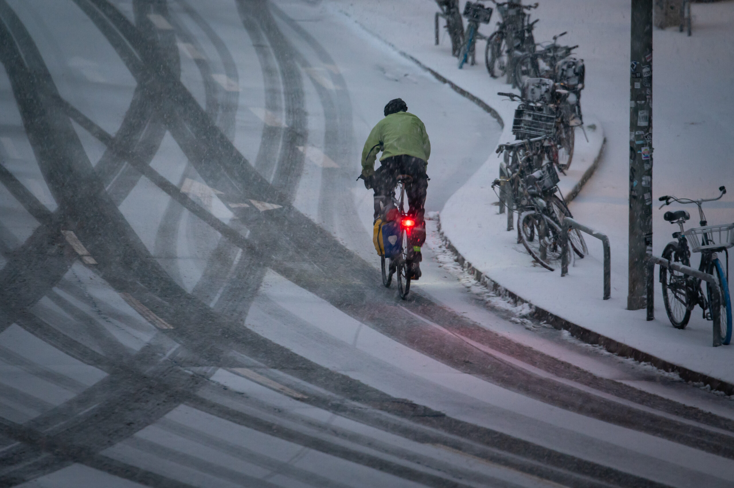 Ein Fahrradfahrer fährt am Morgen eine verschneite Straße entlang.